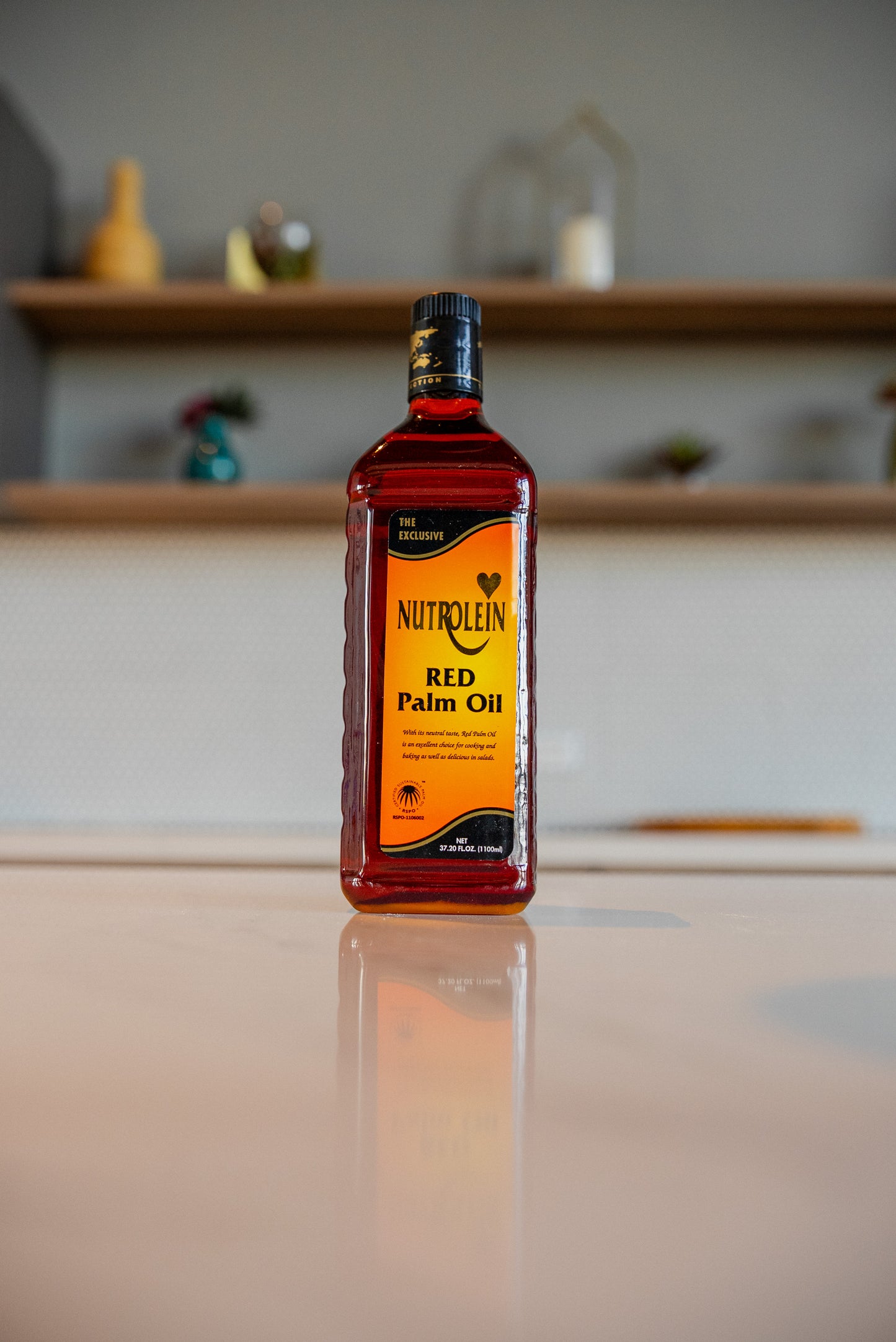 Bottle of Nutrolein Red Palm Oil on a reflective surface with a blurred background